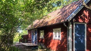 Punainen puutalo, jossa on kuisti, ovi ja ikkuna.