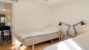 Minimalistinen makuuhuone, jossa on sänky, yöpöydät ja työpöytä.