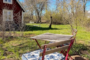 A rustic outdoor seating area with a wooden table and bench, surrounded by grass and trees. - 3 person holiday home in BORGHOLM (BORGHOLM)