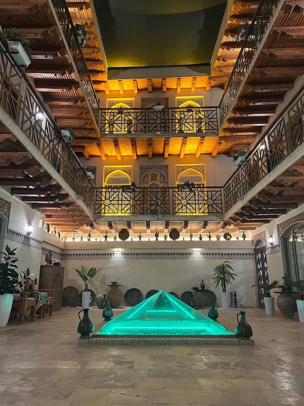 A multi-level atrium with wooden balconies, a central fountain, and traditional decor. - SAFIYA BOUTIQUE HOTEL (Buxoro)