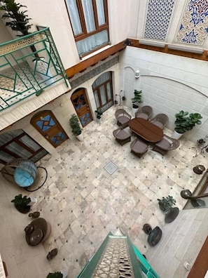 A courtyard with a dining area, potted plants, and a staircase. - SAFIYA BOUTIQUE HOTEL (Buxoro)