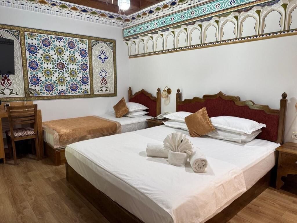 A hotel room with two beds, a wooden desk, and a chair.
