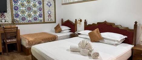 A hotel room with two beds, a wooden desk, and a chair.