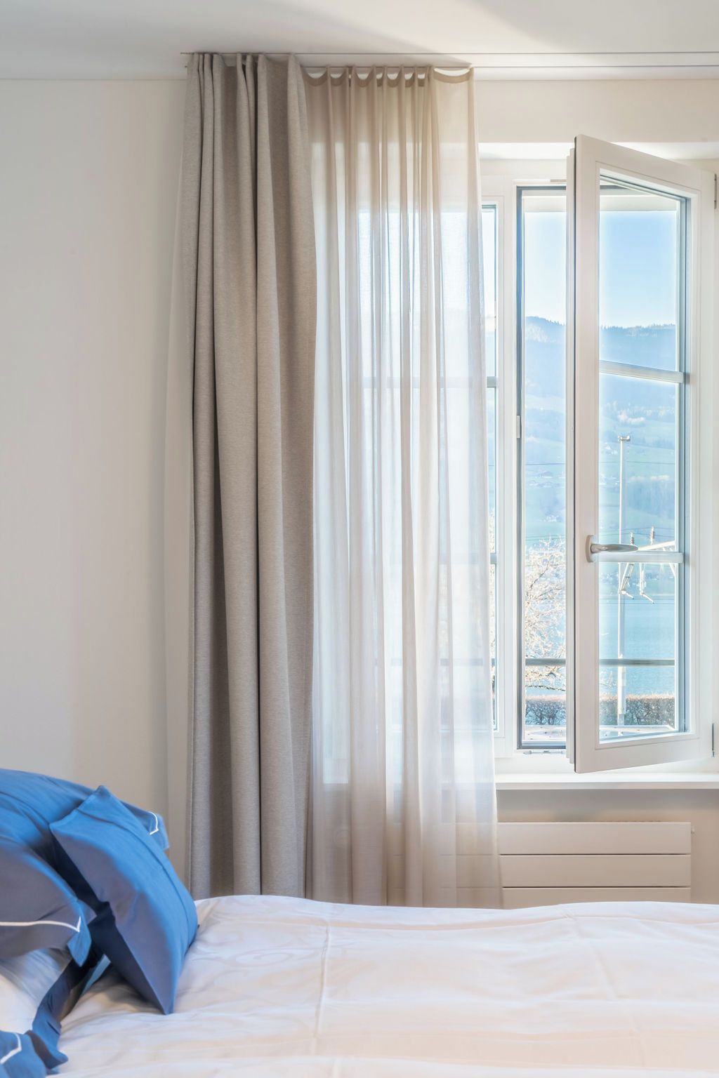 Ein Schlafzimmer mit einem Bett, einem Fenster mit Blick und einem Vorhang.