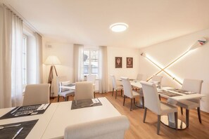 Een hotelkamer met een zithoek, een bed, een raam met gordijnen en een wandlamp.