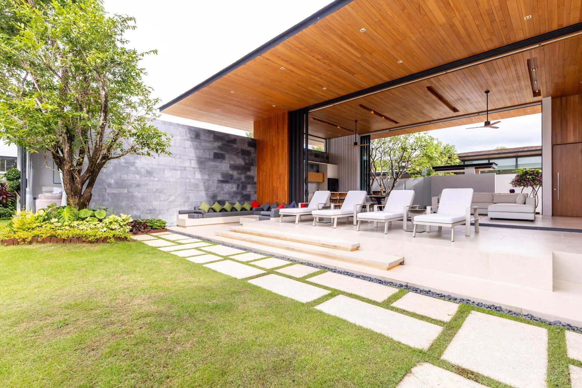 Un espace extérieur moderne, aménagé avec des sièges, et un chemin de pierre menant à une terrasse en bois.