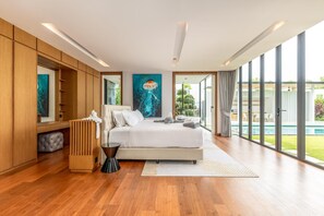 Een moderne slaapkamer met een groot bed, houten lambrisering, een schilderij en uitzicht op een zwembad.