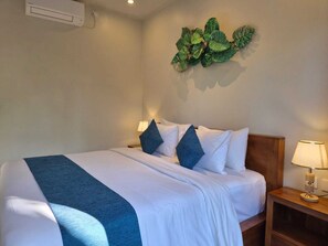 A hotel room with a bed, a nightstand, a lamp, and a wall-mounted decorative piece. - Lavana Ubud (Ubud)