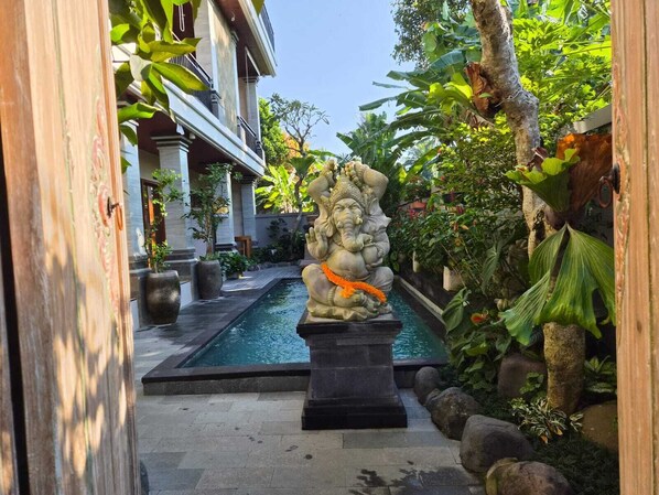A stone statue of a deity with an elephant head, placed in a garden with a pool and tropical plants. - Lavana Ubud (Ubud)