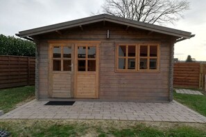 A small wooden cabin with a sloped roof, two doors, and two windows. - Holiday apartment Wolkenbruch (Trendelburg \/Friedrichsfeld)