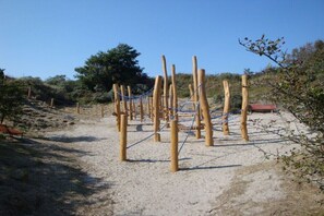 Ein sandiger Außenbereich mit Holzbalken und Seilen, möglicherweise zum Klettern oder für Übungen.