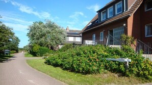 A residential street with houses, a paved road, and a signpost. - Holiday apartment with 2 bedrooms (Baltrum)