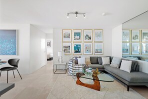 A modern living room with a glass coffee table, grey sofa, and framed cityscape pictures on the wall. - Penthouse Near Taronga Zoo w/ Iconic Harbour Views (Mosman)