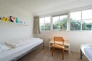 A bedroom with a bed, a chair, a desk, and a window with a view of trees. - Holiday apartment in Buren with swimming pool (Buren)