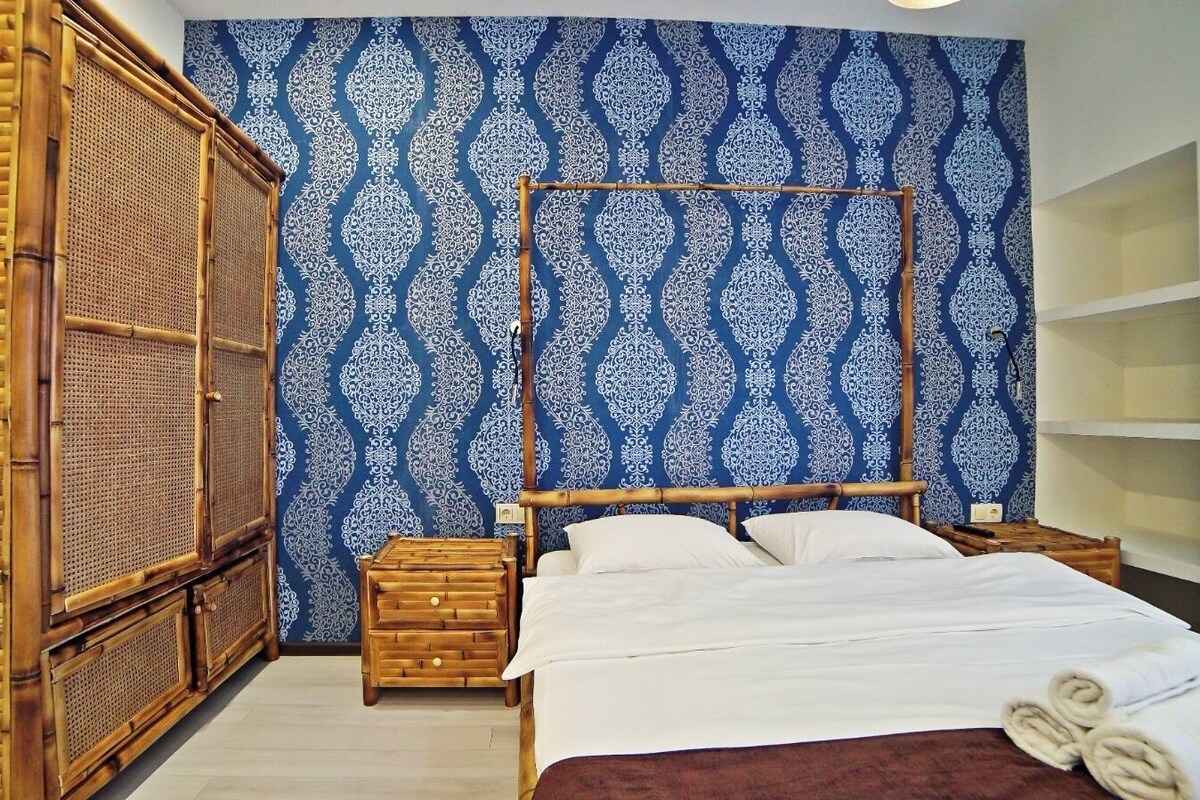 A room with a bed, wooden furniture, and a patterned wall.