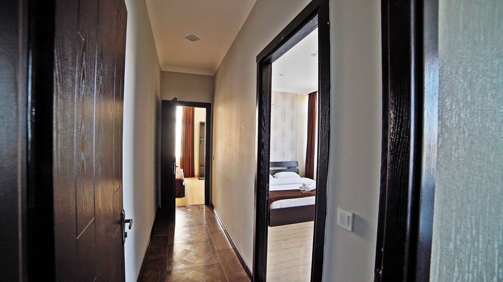 Un pasillo que da a un dormitorio con una cama, una puerta e interruptor de luz.