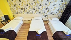 A hotel room with three single beds, a small desk, a chair, and a patterned wall. - Plaza Inn Batumi (Batumi)