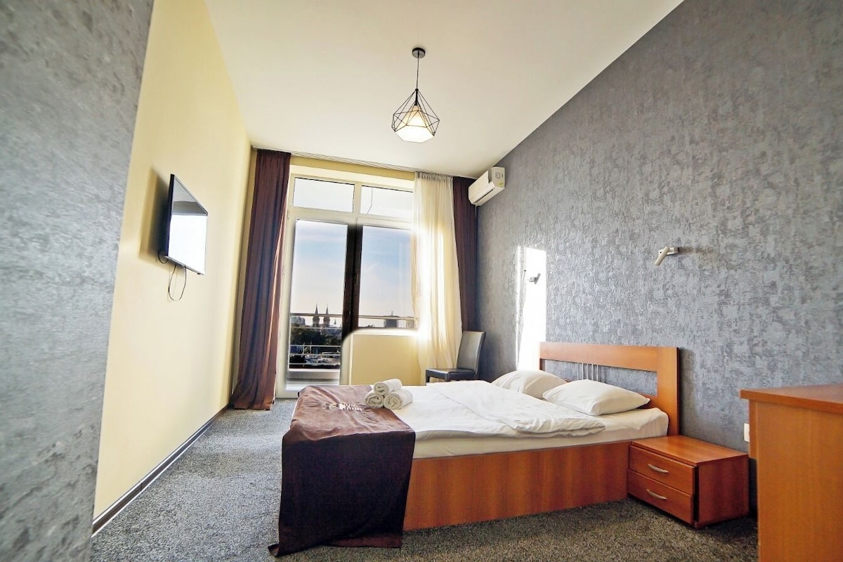 A hotel room with a bed, bedside table, and a desk.
