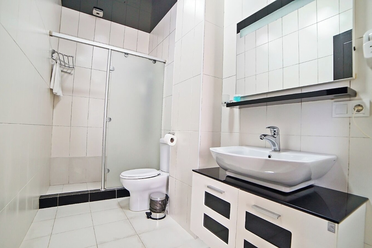 A bathroom with a white toilet, a sink with a black countertop, and a shower area.