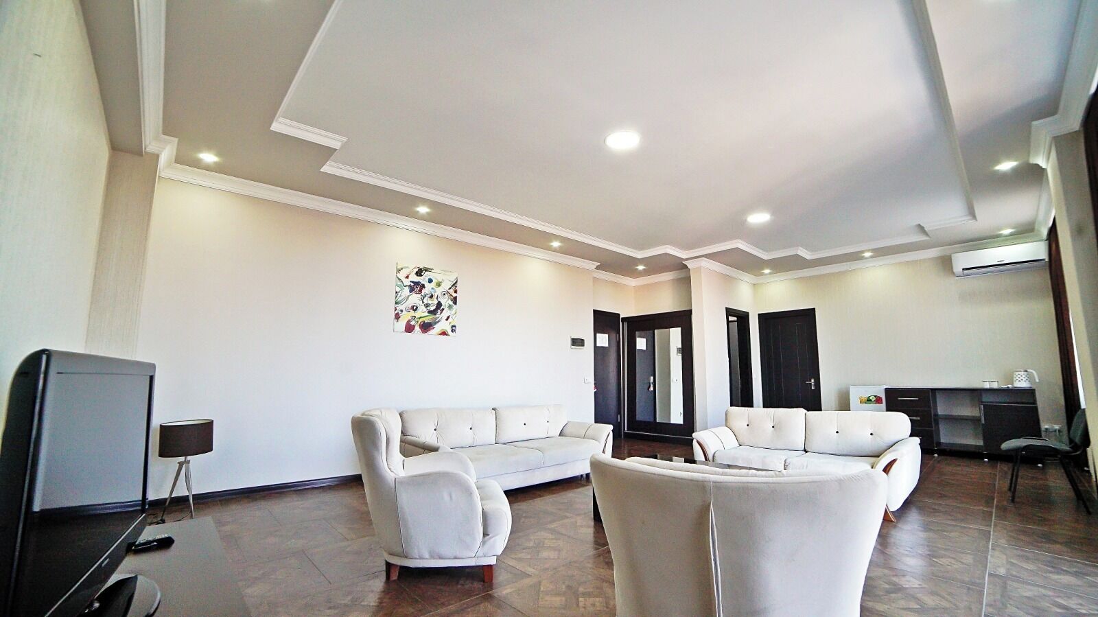 Una sala moderna con un conjunto de sofá, un televisor y una zona de escritorio.