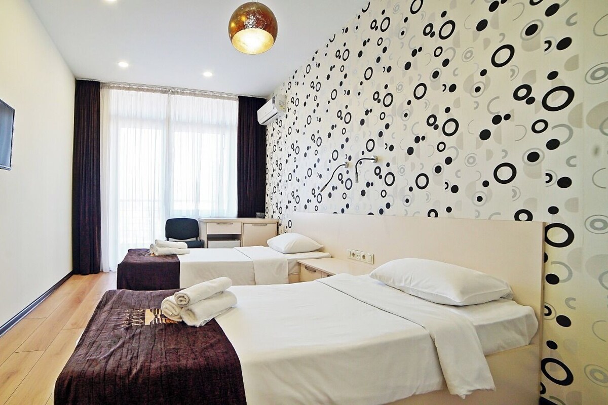 A hotel room with two beds, a desk, a chair, and a TV mounted on the wall.
