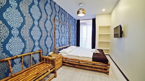Una habitación con cama, una mesita de noche, un televisor y una pared con diseño decorativo.