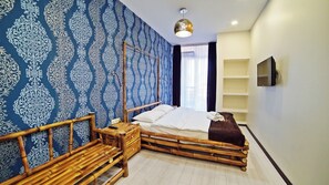 A room with a bed, a bedside table, a TV, and a wall with a patterned design. - Plaza Inn Batumi (Batumi)