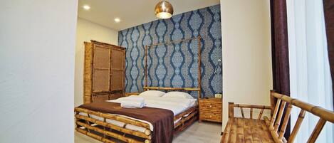 A room with a bed, a wooden chair, a nightstand, and a wall with a patterned wallpaper.