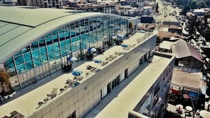 Un hotel con una gran piscina de vidrio y asientos al aire libre.