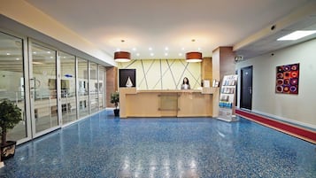 A reception area with a reception desk, a potted plant, and a wall-mounted information stand.