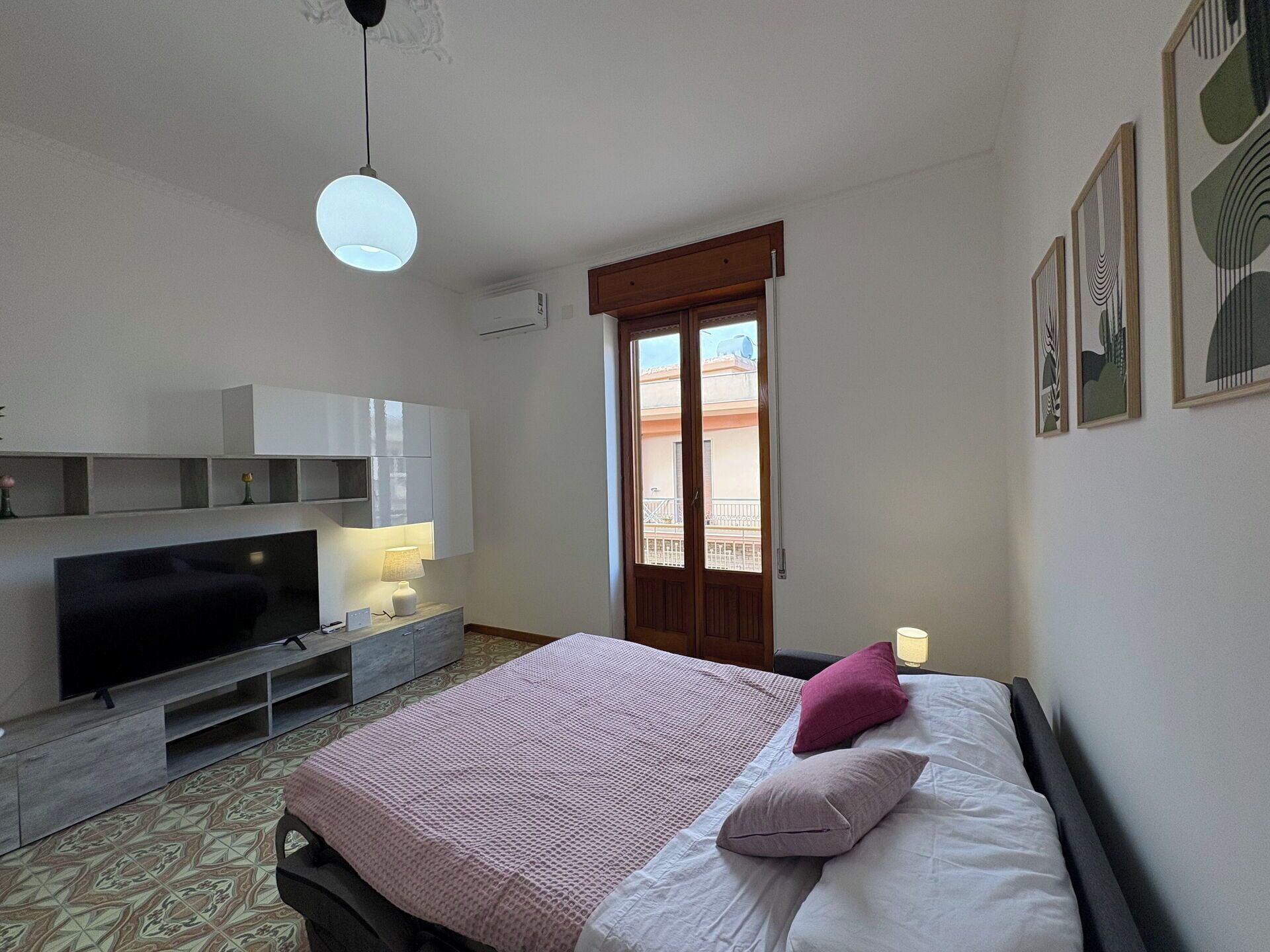 Una camera da letto con un letto, una TV, una scrivania e una finestra.