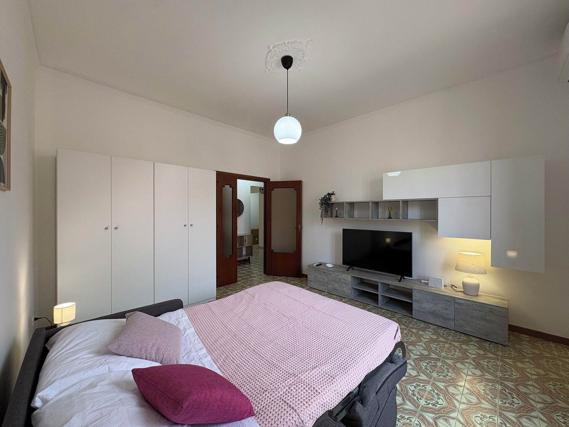 A bedroom with a bed, a TV, and a wardrobe.