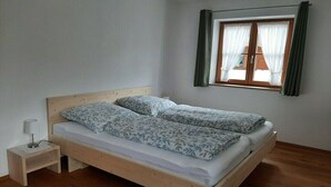 Ein Einzelbett mit hölzernem Gestell und einem Nachttisch mit Lampe.