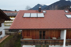A traditional chalet with a red-tiled roof, wooden shutters, and a balcony with seating.