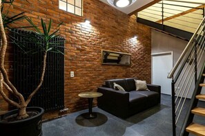 A modern interior with a brick wall, a black leather sofa, a small round table, and a staircase. - Holiday apartment with 1 bedroom (Twistetal-Ober Waroldern)