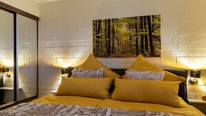 A bedroom with a bed, two nightstands, a painting on the wall, and a mirror. - Holiday apartment with 1 bedroom (Twistetal-Ober Waroldern)