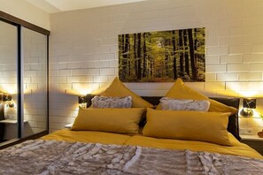 Un dormitorio con cama, dos mesitas de noche, un cuadro en la pared y un espejo.