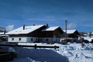 Ein schneebedecktes Gebäude mit Holzfassade, geneigtem Dach und einem sichtbaren Schornstein.