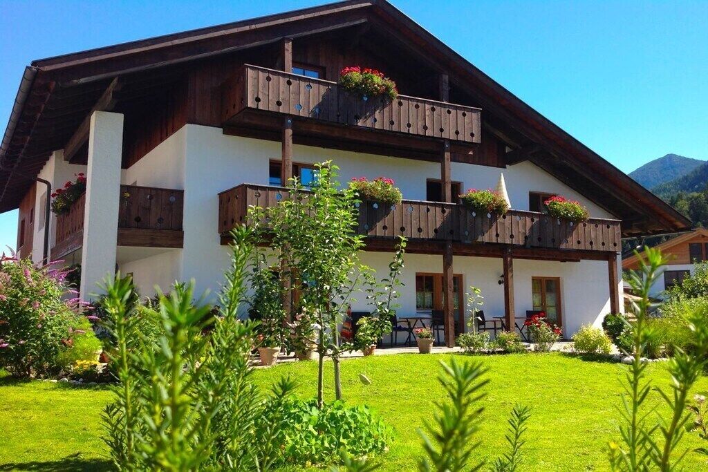 Eine zweistöckige Chalet mit Balkonen, einem Garten und einem Blick auf die Berge.