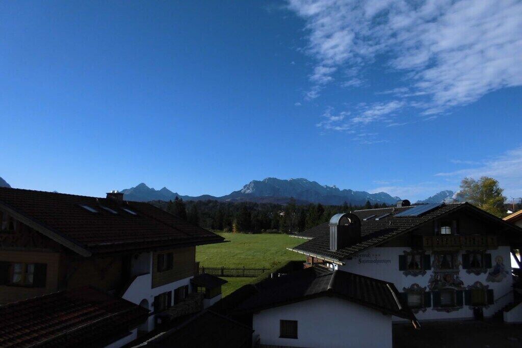 A rural village with traditional buildings, a green field, and mountains in the background.