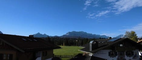 A rural village with traditional buildings, a green field, and mountains in the background.