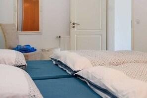 Ein Schlafzimmer mit zwei Betten, einem Sessel und einem Fenster.