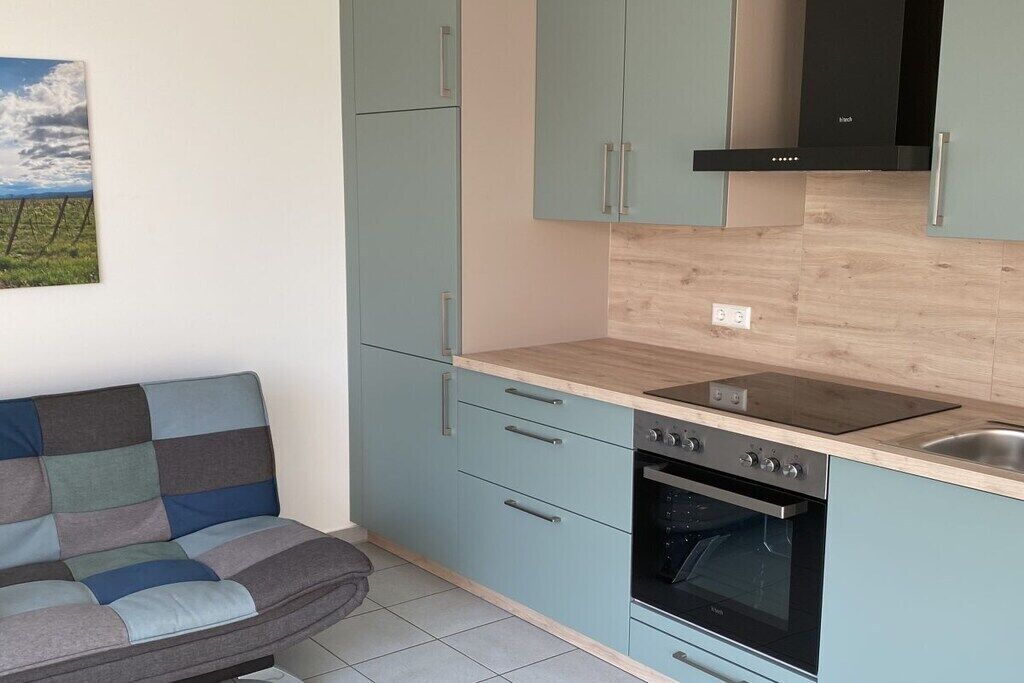 Una cocina con armarios azul claro, estufa negra y encimera de madera.
