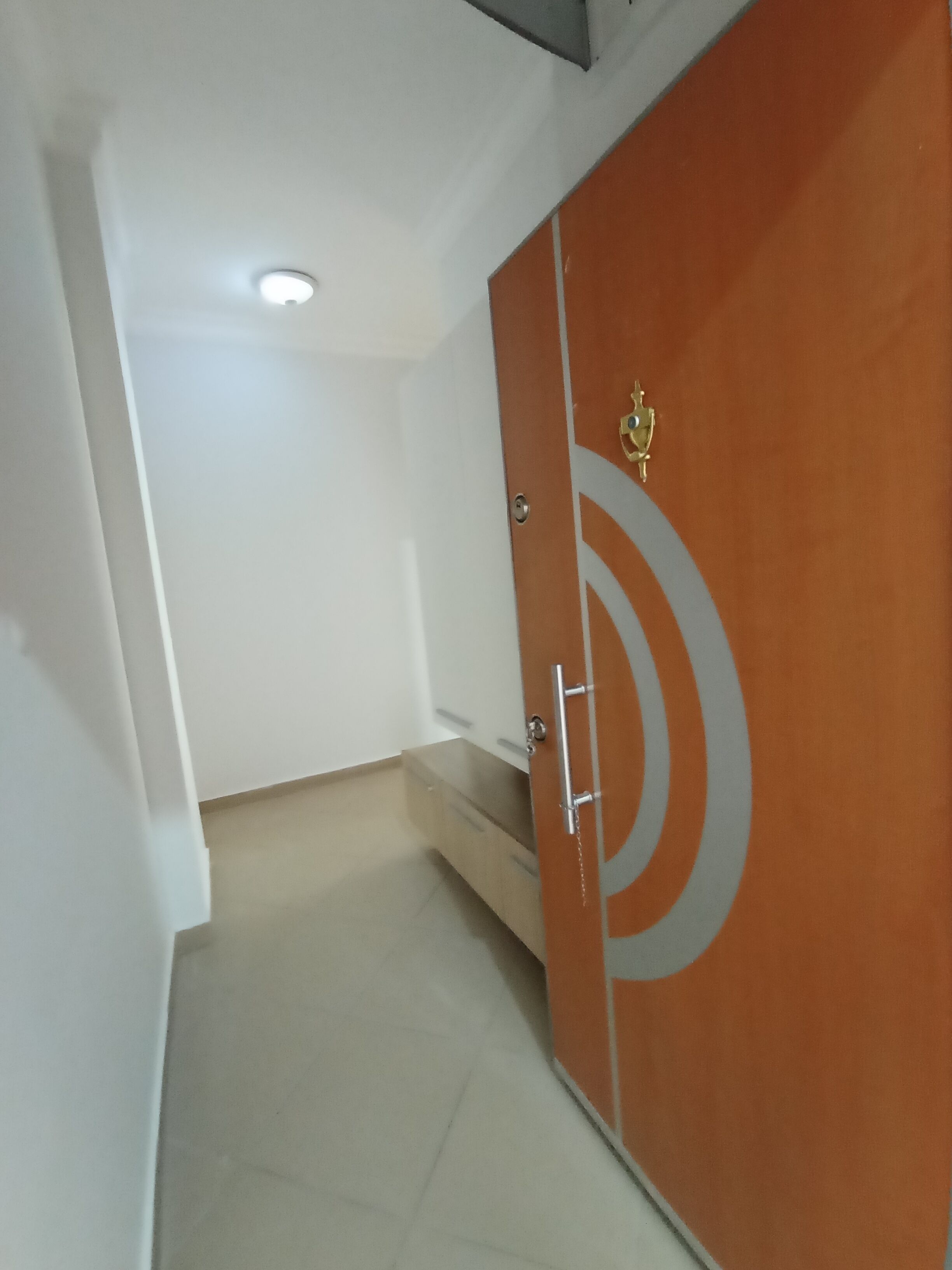 Un couloir avec une porte double fermée, une petite marche menant à un palier et un luminaire au plafond.