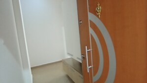 Un pasillo con una puerta doble cerrada, un pequeño escalón que lleva a un rellano y una lámpara en el techo.