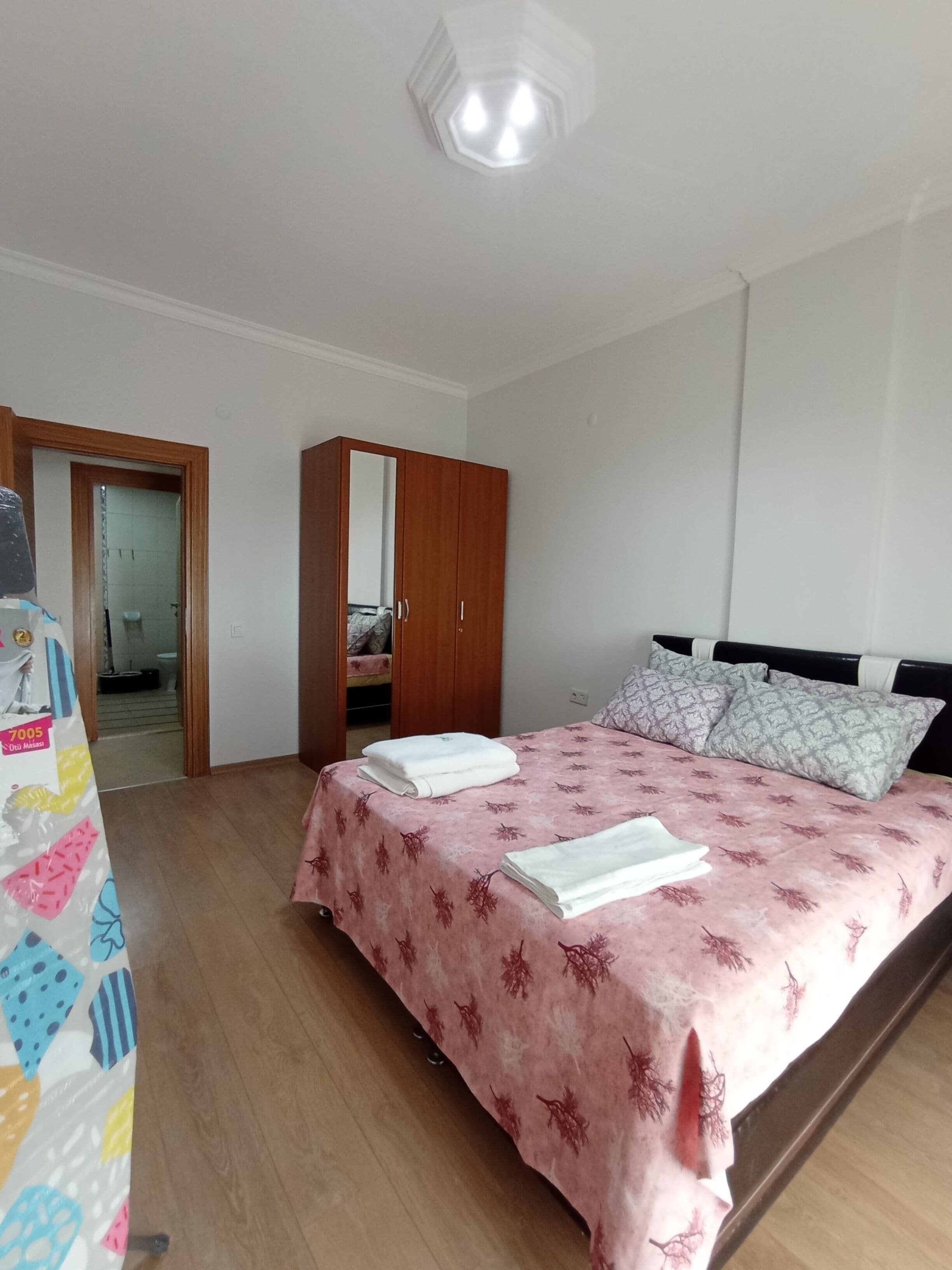Une chambre à coucher avec un lit, une armoire et une salle de bain visible à travers une porte ouverte.