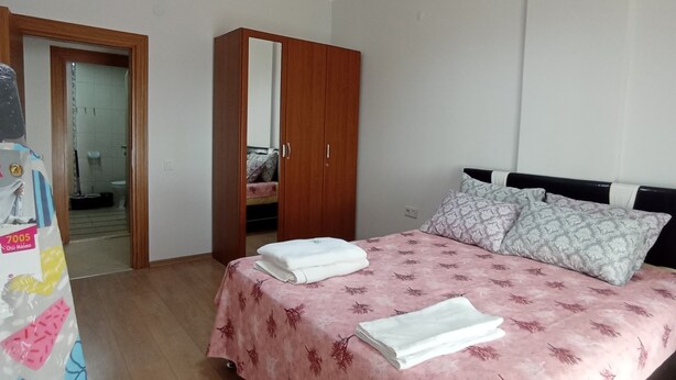 Un dormitorio con cama, armario y baño visible a través de una puerta abierta.