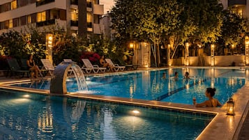 A swimming pool with lounge chairs, a waterfall feature, and a stone structure.