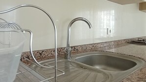 Una cocina con encimera de granito, pileta de acero inoxidable y muebles de cocina modernos.