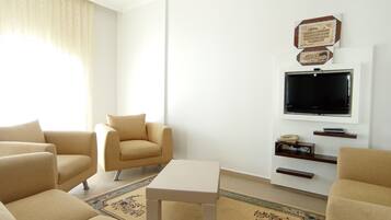 Una sala de estar con un sofá, una mesa de centro, un televisor y un tapete decorativo.